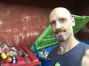 Jon standing by dumpster with rescued food on the lid