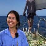 Emelie holds arrowroot corm while Jon stands at the bow looking over the ocean